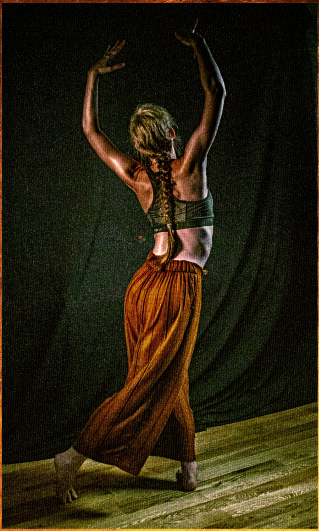 Dancer in warm textured light, arms raised